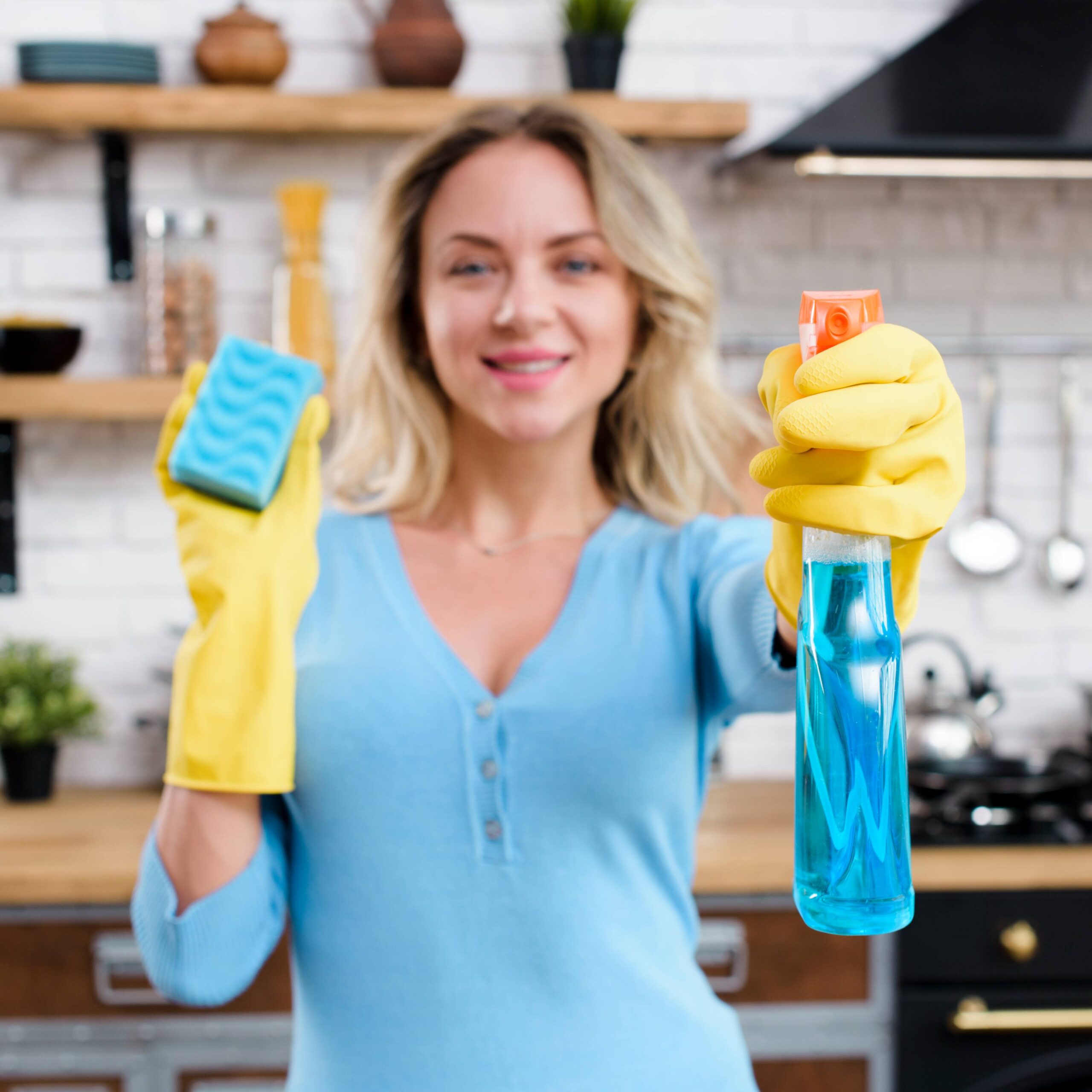 smiling woman wearing rubber gloves holding detergent with sponge 1 scaled